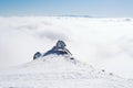 The summit of a snowy mountain with a clear blue sky on a sunny day overlooking the valley covered by fog Royalty Free Stock Photo