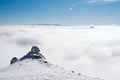 The summit of a snowy mountain with a clear blue sky on a sunny day overlooking the valley covered by fog Royalty Free Stock Photo