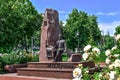 Sculpture of Mikhail Lushpa among the green blossoming nature in Sumy - side view. Bronze man