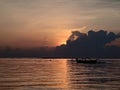 The sun arise behind the cloud over the horizon with floating fishing boat on sea background.