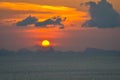 Sun ball hides behind clouds dramatic and colorful sunset over ocean