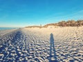 Sun beach and sea with long human shade and lighthouse