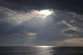 Sun beams in clouds and silvery path on calm sea surface, cloudy background Royalty Free Stock Photo