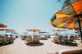 Sun beds on tropical beach with calm sky.