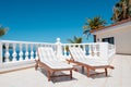 Two sun beds on villa terrace with ocean and palm tree background