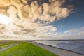 Sun behind the clouds over the dike at the Wadden sea in Lauwersmeer Royalty Free Stock Photo