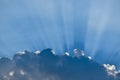 Sun behind the clouds with sun rays streaks in the cloudy blue sky with copy space Royalty Free Stock Photo