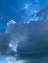 Sun behind dark clouds with sun rays on blue sky background. Light Breaking Behind Clouds Royalty Free Stock Photo