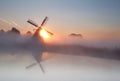 Sun behind windmill and fog Royalty Free Stock Photo