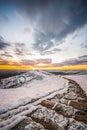 Sun below the horizon icy frozen snow covered winding stone footpath path way leading up mountain side sunrise winter morning.