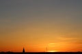 Sun below the horizon and the roof of the church with a cross on the background fiery dramatic orange sky at sunset or Royalty Free Stock Photo