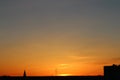 Sun below the horizon and the roof of the church with a cross, television antenna in the background fiery dramatic Royalty Free Stock Photo