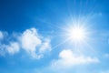 The sun with bright rays in the blue sky with white light clouds. Royalty Free Stock Photo