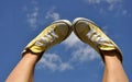 Sun burnt woman's feet in bright yellow sneakers against the deep blue sky background