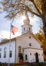 Sun burst behind a beautiful white church with an American flag flying high. Royalty Free Stock Photo