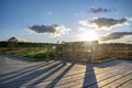 Sun casting low light during calm Sunset in summer over Wooden footpath Royalty Free Stock Photo