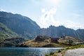 Sun casting rays on a mountain lake with mountain chalet and mountain in the background and puffy clouds above