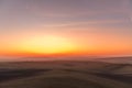 The sun caught during the last moment before setting beyond the horizon with view of a field covered with fog and the farms and