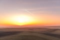 The sun caught during the last moment before setting beyond the horizon with view of a field covered with fog and the farms and
