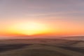 The sun caught during the last moment before setting beyond the horizon with view of a field covered with fog and the farms and