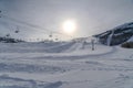 Sun and cloudy sky over ski lifts and mountain