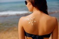 Sun cream. Suntan lotion beautiful woman applying on tanned shoulder in form of the sun. Sunscreen solar cream Royalty Free Stock Photo