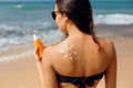 Sun cream. Suntan lotion beautiful woman applying on tanned shoulder in form of the sun. Sunscreen solar cream. Skin care. Sun pro Royalty Free Stock Photo