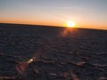 Sun on curved horizon over baked, dry cracked crust of Makgadikgadi Pans National Park, scenic large flat area of salt pan desert