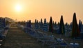 The sun of dawn illuminates the still deserted beach with the beach umbrellas still closed