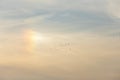 A sun dog atmospheric optical phenomenon in the sky, with birds flying in the distance Royalty Free Stock Photo