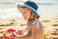 The sun drawing sunscreen ,suntan lotion on baby boy back. Caucasian child is sitting with plastic container of sunscreen and toys Royalty Free Stock Photo