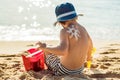 The sun drawing sunscreen ,suntan lotion on baby boy back. Caucasian child is sitting with plastic container of sunscreen and toys Royalty Free Stock Photo