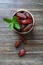 Sun-dried dates fruits and fresh mint leaves in a ceramic bowl on a wooden table. Royalty Free Stock Photo