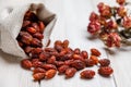 Sun-dried rosehip berries scattered from a linen bag on a light wooden table. The concept of traditional medicine, treatment with Royalty Free Stock Photo