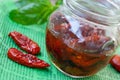 Sun-dried tomatoes with basil, garlic, rosemary and spices in a glass jar on a green napkin Royalty Free Stock Photo