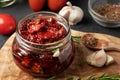 Sun-dried tomatoes with garlic, rosemary and spices in a glass jar on an olive wood cutting board Royalty Free Stock Photo