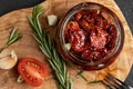 Sun-dried tomatoes with garlic, rosemary and spices in a glass jar on an olive wood cutting board, top view, flat lay Royalty Free Stock Photo