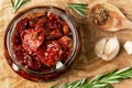 Sun-dried tomatoes with garlic, rosemary and spices in a glass jar on an olive wood cutting board, top view, flat lay Royalty Free Stock Photo