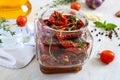 Sun-dried tomatoes with herbs, garlic in olive oil in a glass jar on a light background Royalty Free Stock Photo