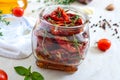 Sun-dried tomatoes with herbs, garlic in olive oil in a glass jar on a light background Royalty Free Stock Photo