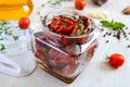 Sun-dried tomatoes with herbs, garlic in olive oil in a glass jar on a light background Royalty Free Stock Photo