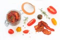 Sun-dried tomatoes with olive oil in glass jar, surrounded with fresh and dry tomatoes, rosemary, pepper and sea salt