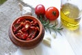 Sun-dried tomatoes with spices and garlic in a clay pot. Nearby is a bottle with olive oil, tomatoes, rosemary and garlic Royalty Free Stock Photo