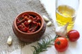 Sun-dried tomatoes with spices and garlic in a clay pot. Nearby is a bottle with olive oil, tomatoes, rosemary and garlic Royalty Free Stock Photo