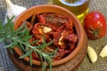 Sun-dried tomatoes with spices and garlic in a clay pot. Nearby is a bottle with olive oil, tomatoes, rosemary and garlic Royalty Free Stock Photo