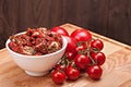 Sun dried tomatoes in white bowl and heap of ripe fresh tomatoes