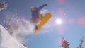 SUN FLARE, CLOSE UP: Excited snowboarder jumps over sun in mountain backcountry