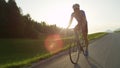 SUN FLARE: Pro road cyclist racing through the countryside in the afternoon.