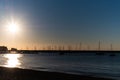 Sun flare shining on a blue solid morning sky on a quiet sea shore landscape