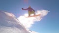 SUN FLARE: Young snowboarder performs epic jump on perfect powder snow slope.